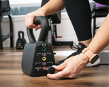 Close-up of adjustable kettlebell being set to 16 lbs by a woman in a modern home gym, showcasing compact strength training gear from Luna Fitness.