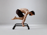 A male athlete performing push-ups on mini parallettes, showcasing strength and control in a home gym setting with high-quality calisthenics equipment