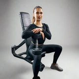 a female model sitting on black adjustable bench holding a dumbbell on her right knee, ideal for home gyms, is displayed on a white background. The bench offers multiple incline positions, allowing for versatile workouts. It features a padded seat and backrest for comfort, and the sturdy frame ensures stability during use. The Luna Fitness logo is prominently displayed on the base of the bench