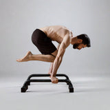 A male athlete performing push-ups on mini parallettes, showcasing strength and control in a home gym setting with high-quality calisthenics equipment