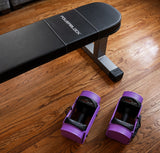 Nomad Powerblock weight bench on a wooden floor with purple/lavender sport 24 adjustable dumbbells
