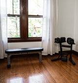 Home gym setup with the nomad weight bench and adjustable dumbbell rack in a bright room with large windows and