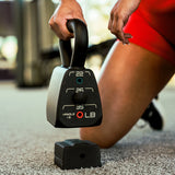 close-up of person adjusting the weight on the adjustable kettlbell on a carpeted floor's living room