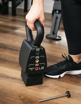 person adjusting weight on the adjustable kettlbell on a wooden floor's living room at home