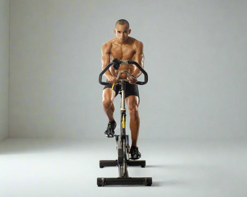 A fit man riding an indoor spin bike, showcasing a high-intensity cardio workout with premium fitness equipment from our Bikes Collection, including fan and spin bikes.