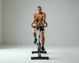 A fit man riding an indoor spin bike, showcasing a high-intensity cardio workout with premium fitness equipment from our Bikes Collection, including fan and spin bikes.